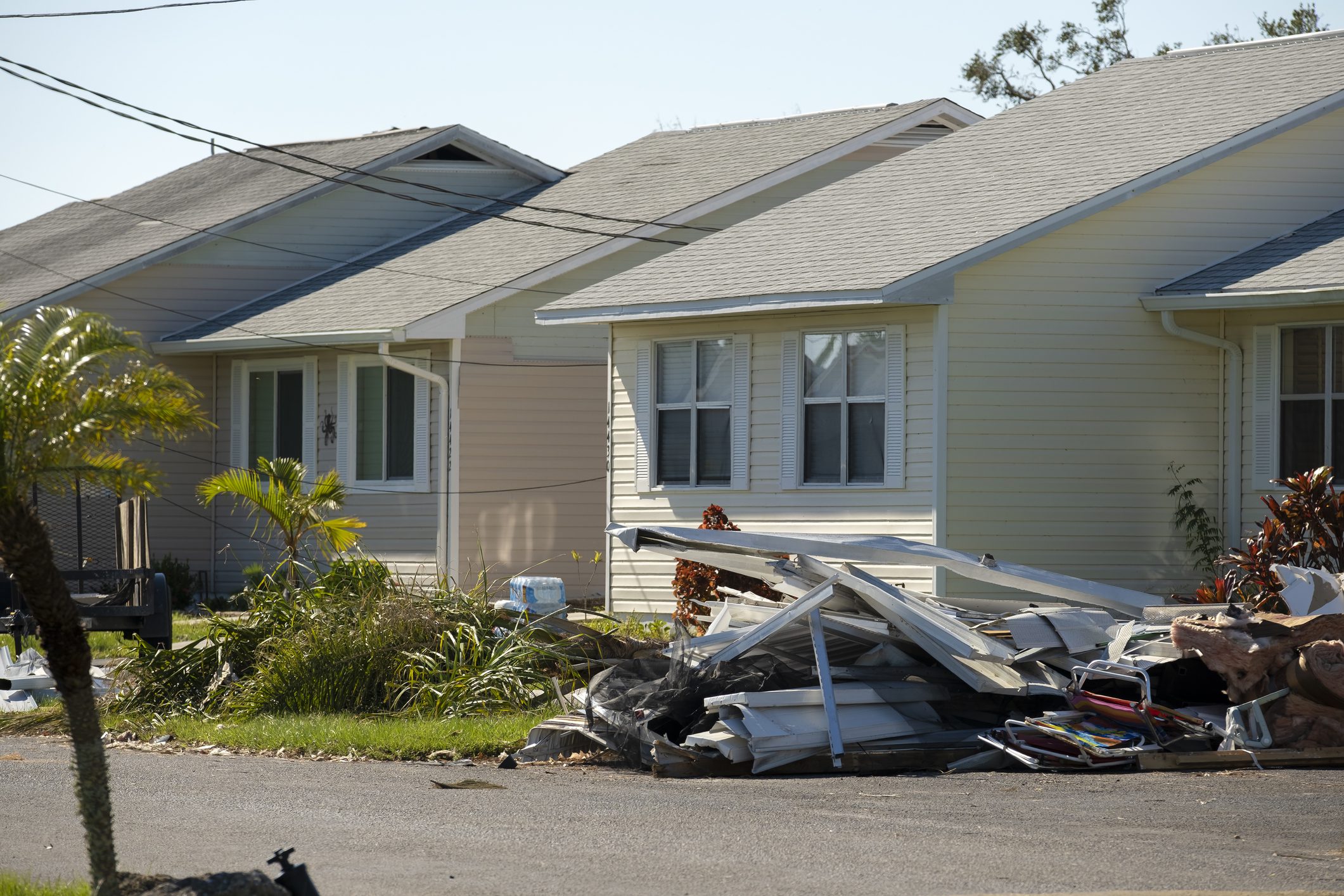 Heaps of debris rubbish on street side near severely damaged by hurricane houses in Florida mobile home residential area. Consequences of natural disaster.
